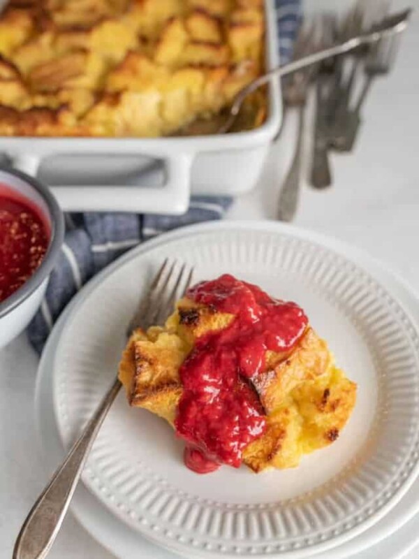 French toast breakfast casserole topped with raspberry sauce on white plate with fork