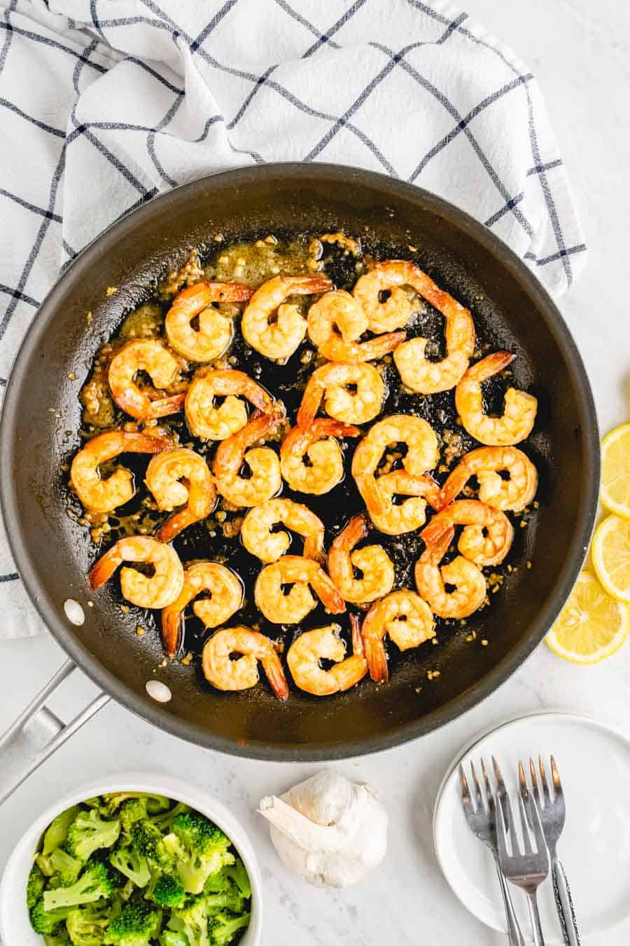 A pan of shrimp cooking in oil and garlic. 
