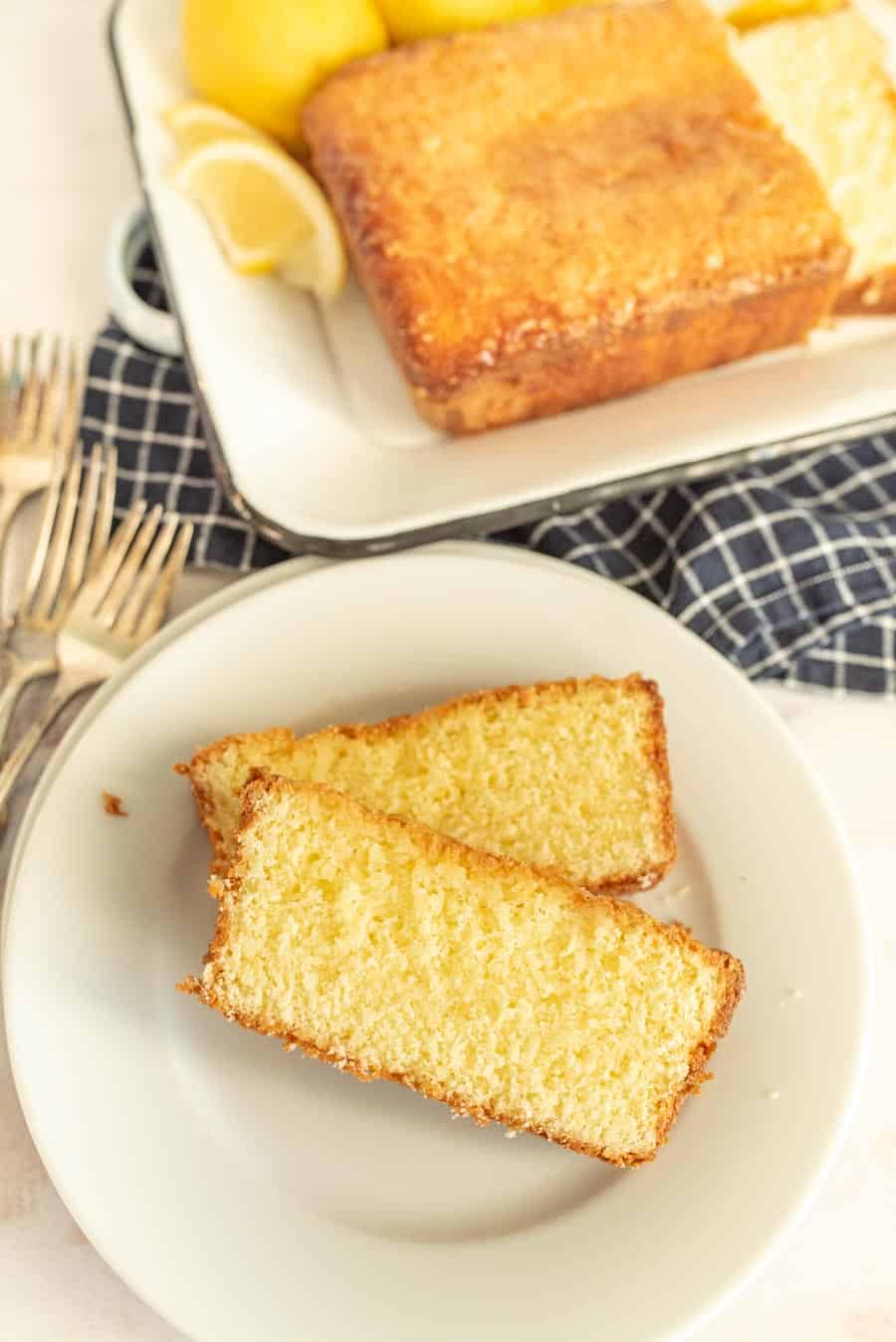 a plate of lemon pound cake slices and a loaf of lemon pound cake in the background