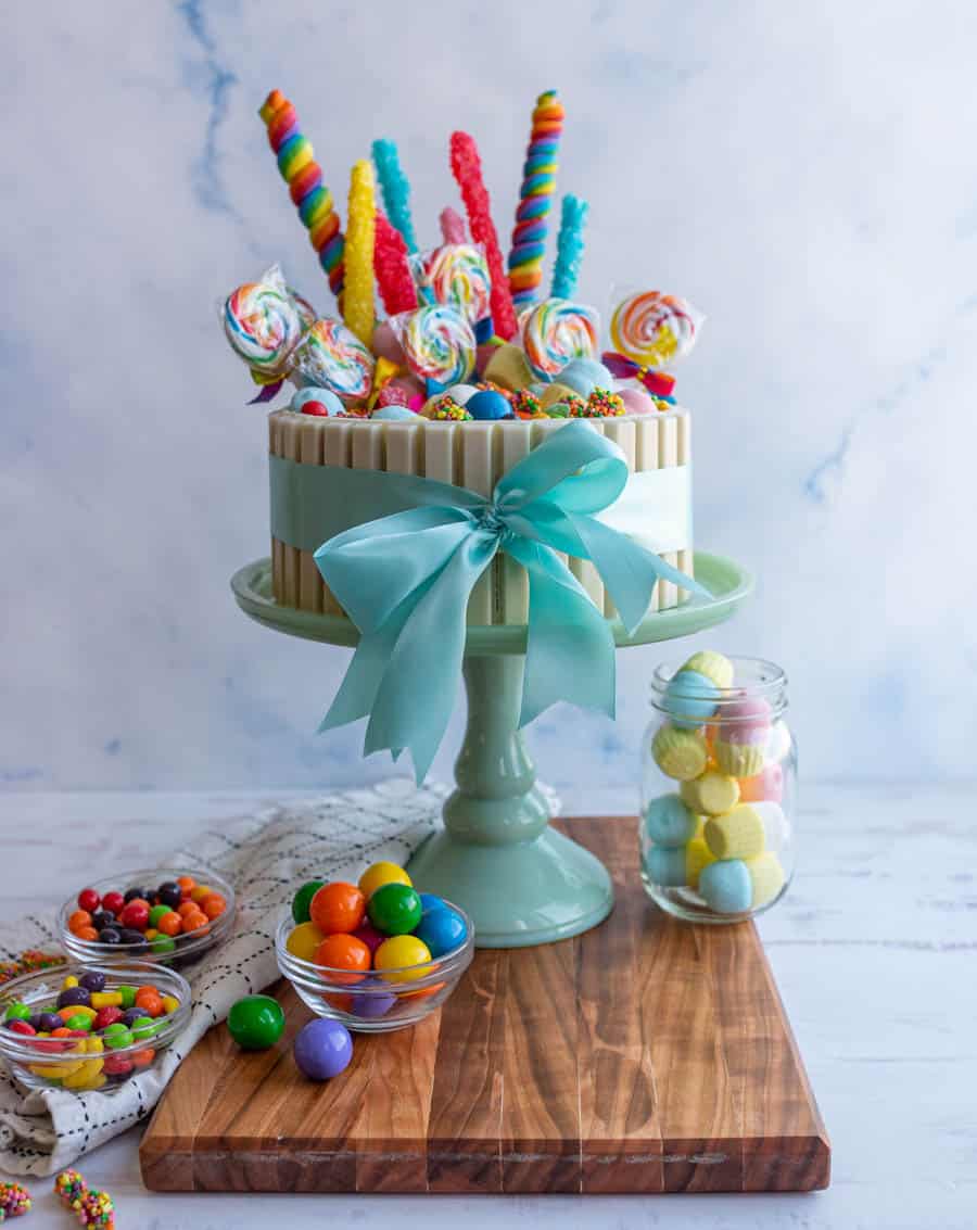 picture of a candy cake on a cake stand with bowls of candy around it