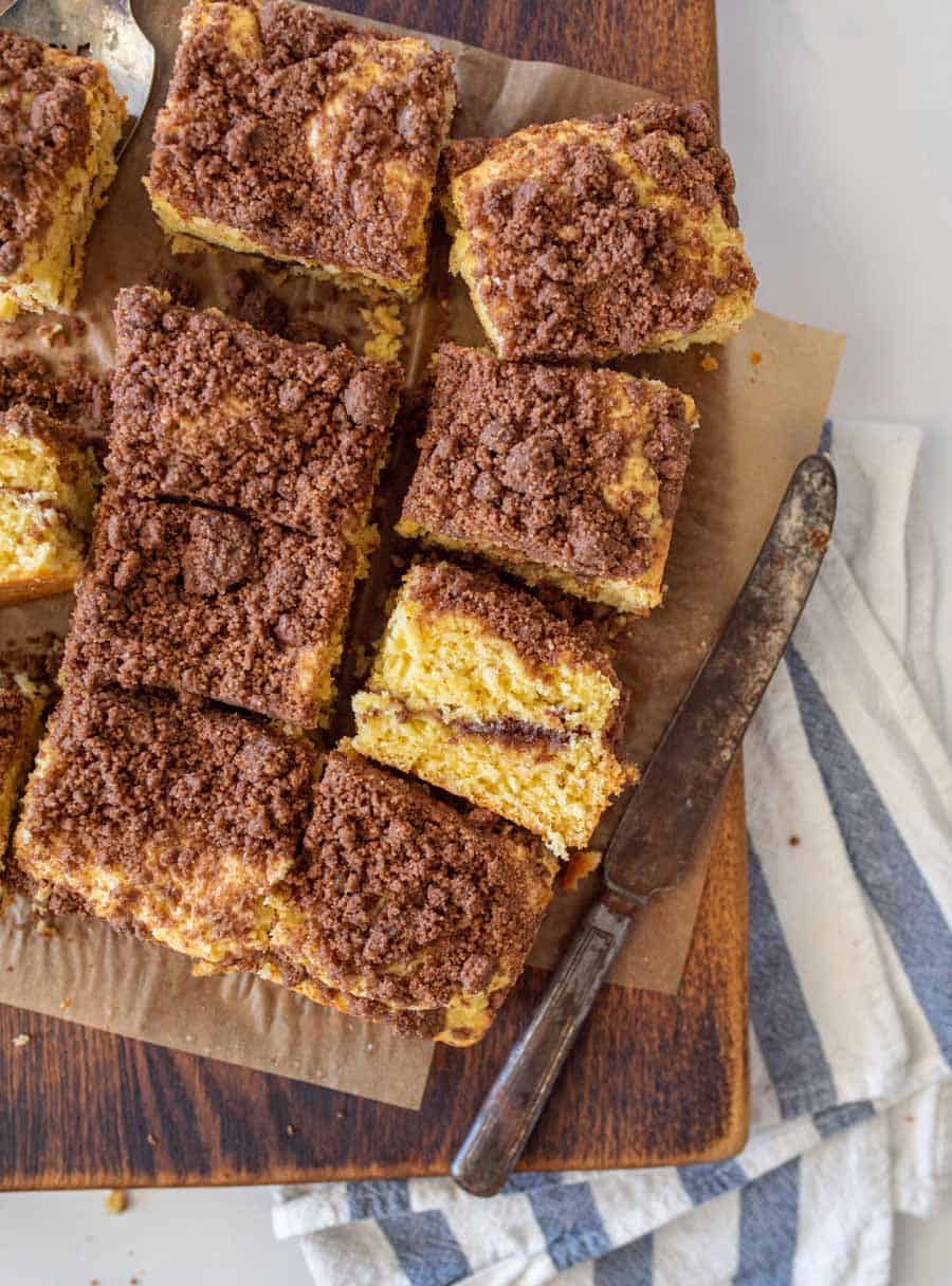 top view of coffee cake on a cutting board, sliced into squares and a knife next to them