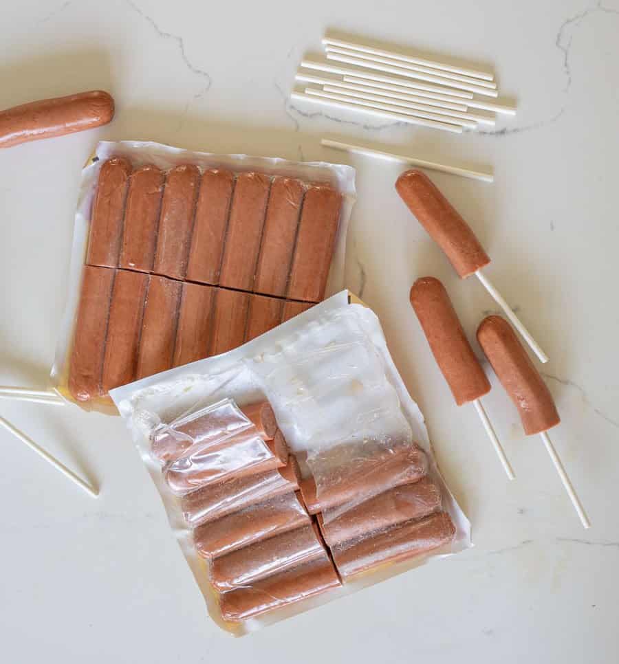 hot dogs cut in half with sticks stuck in them.