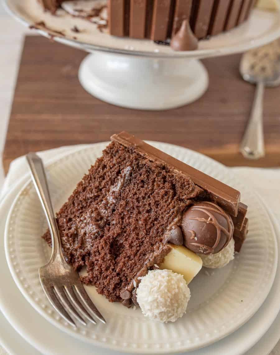 A slice of chocolate candy cake on a white plate with a fork.