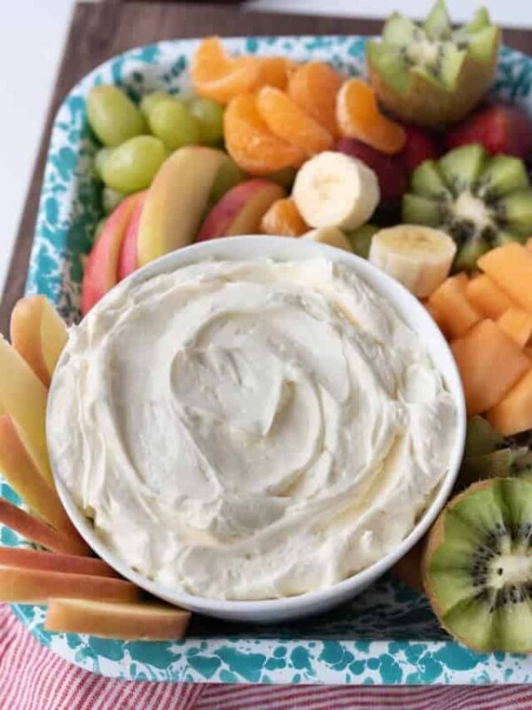 bowl of fruit dip on a tray with a variety of fruit surrounding it