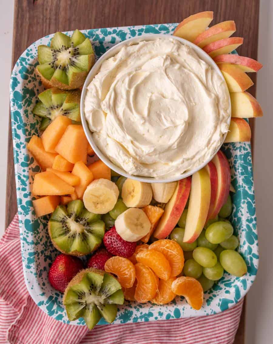 top view of a bowl of fruit dip and different fruits on a tray