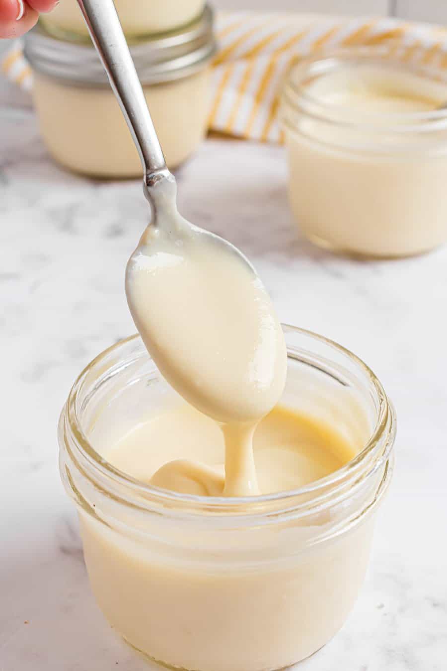 vanilla pudding on spoon above jar of pudding