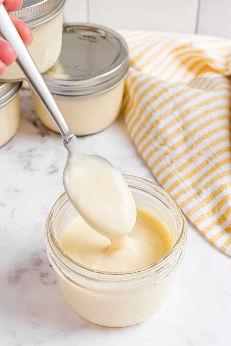 A spoonful of pudding dripping into a  jar of pudding. 