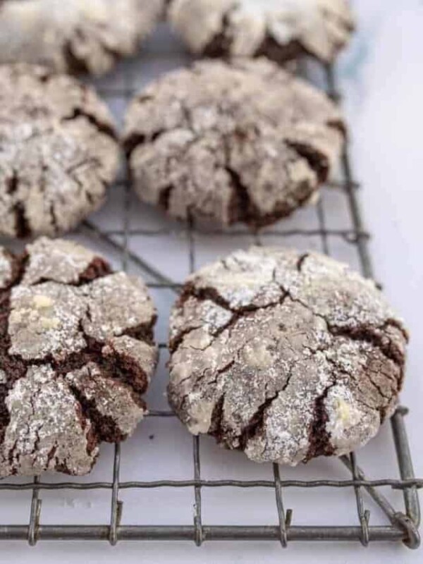 close up top view of a cooling rack cracked cookies that are nearly white on top but the cracks reveals dark chocolaty lines