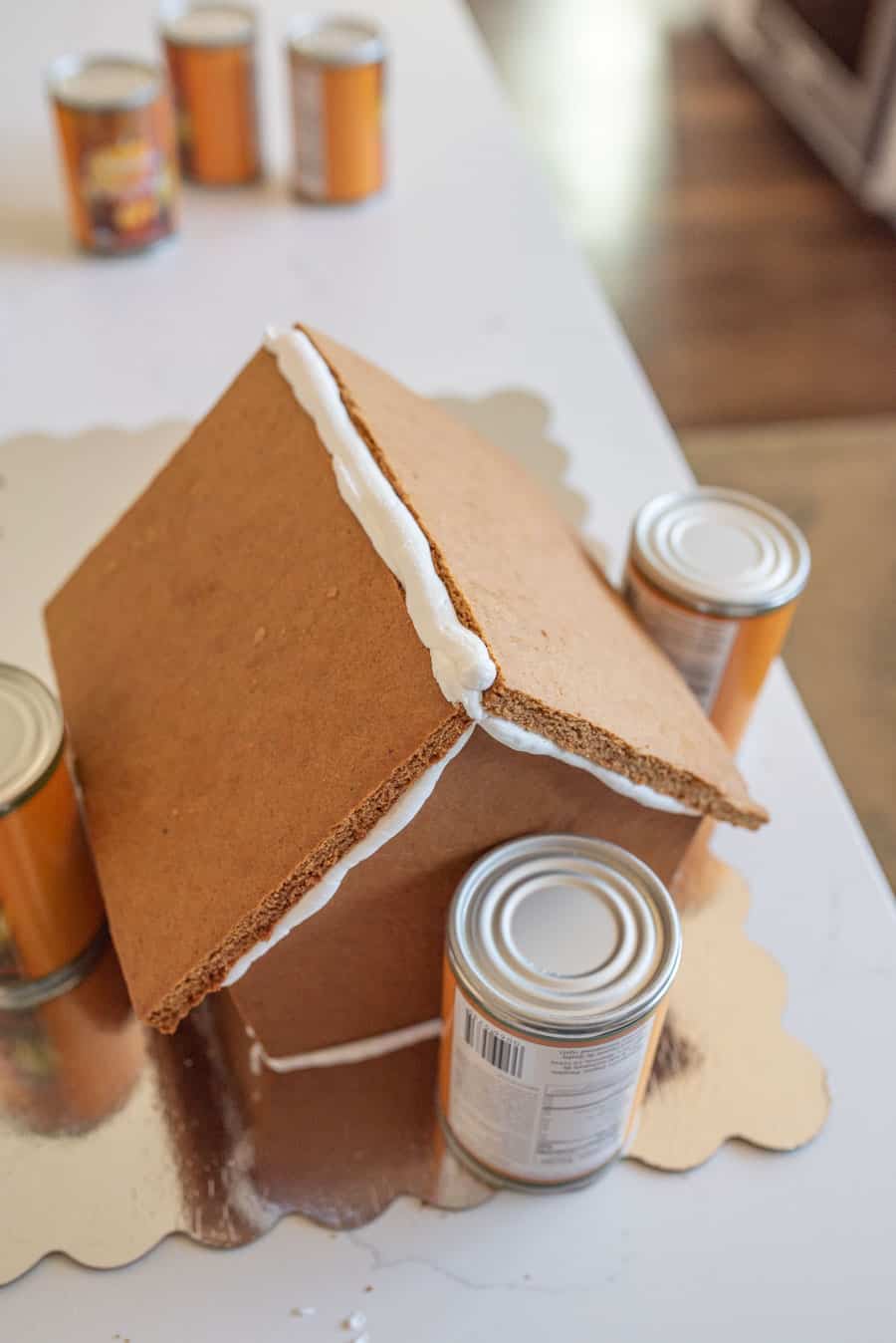 step one of the constructed version of royal icing holding together the beginning of the gingerbread house structure as it dries