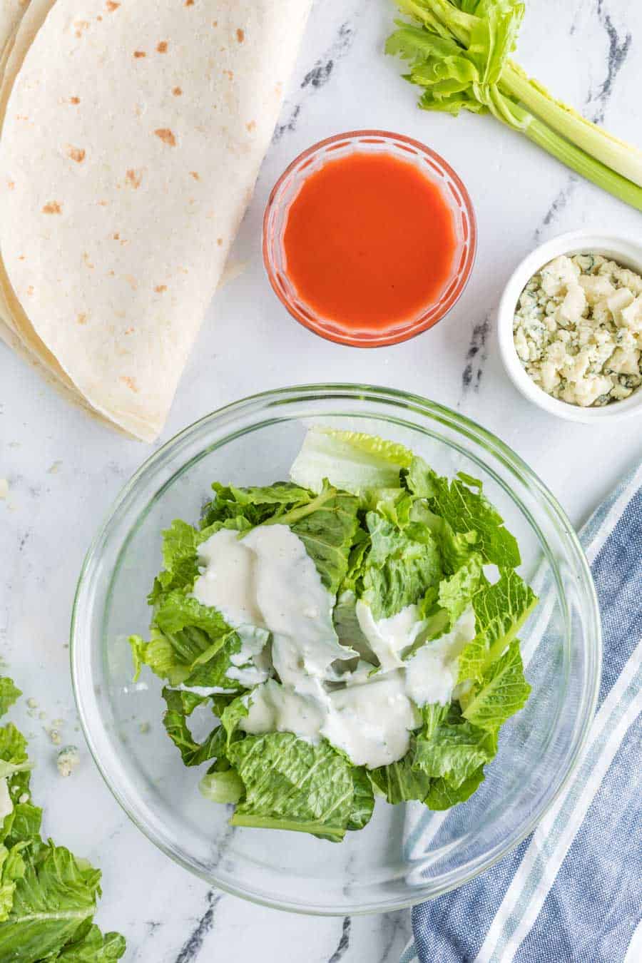 romain lettuce and a dallop of creamy dressing in a clear glass bowl