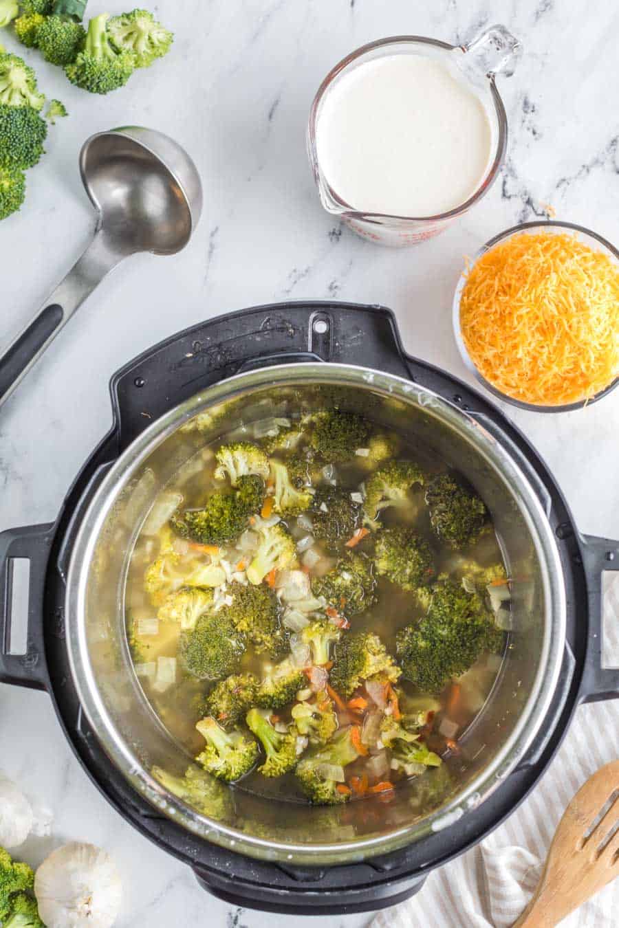 top view of and instant pot with raw vegetables in water beginning to cook down