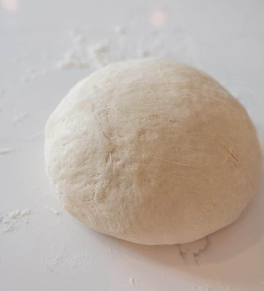 sourdough bread ball rolled onto a white table. 