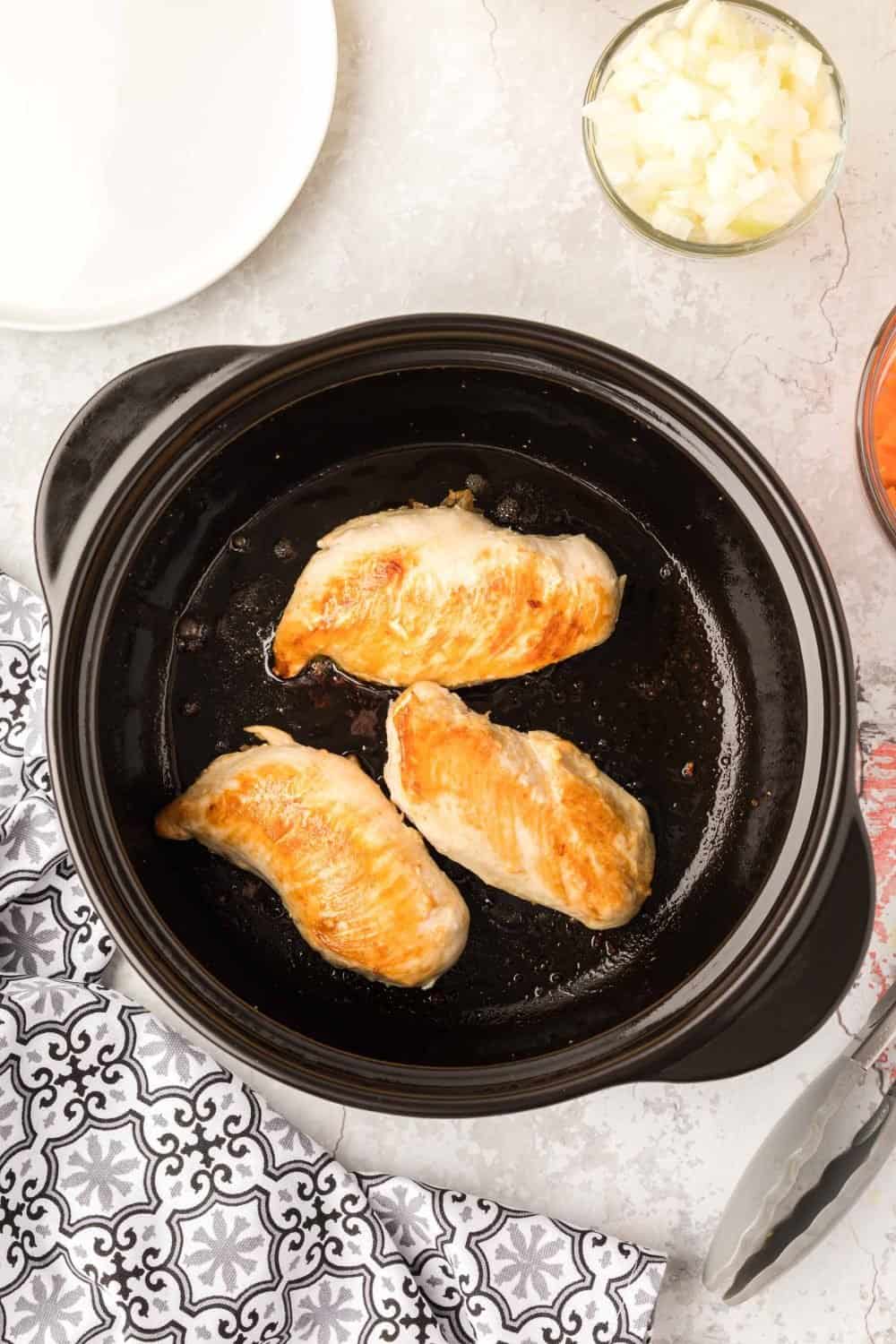 chicken being cooked in a dutch oven