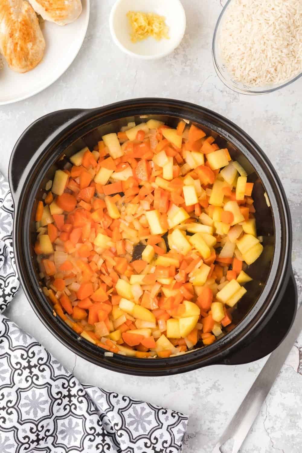 onions, carrots, and apples being sauteed in a pan