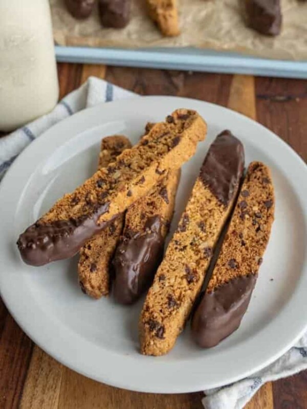 biscotti on a plate with chocolate chips and one end lightly covered in chocolate