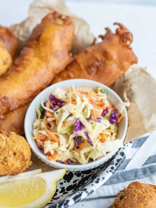 a bowl of coleslaw with fried fish and hush puppies