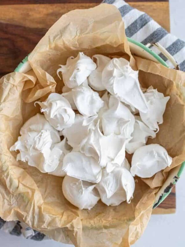 dollops of fluffy looking white divinity candy on parchment stacked in a dish