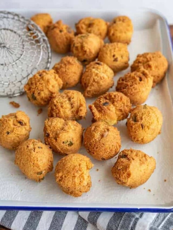 close up of round balls of hush puppies fresh out of the fryer on a baking dish