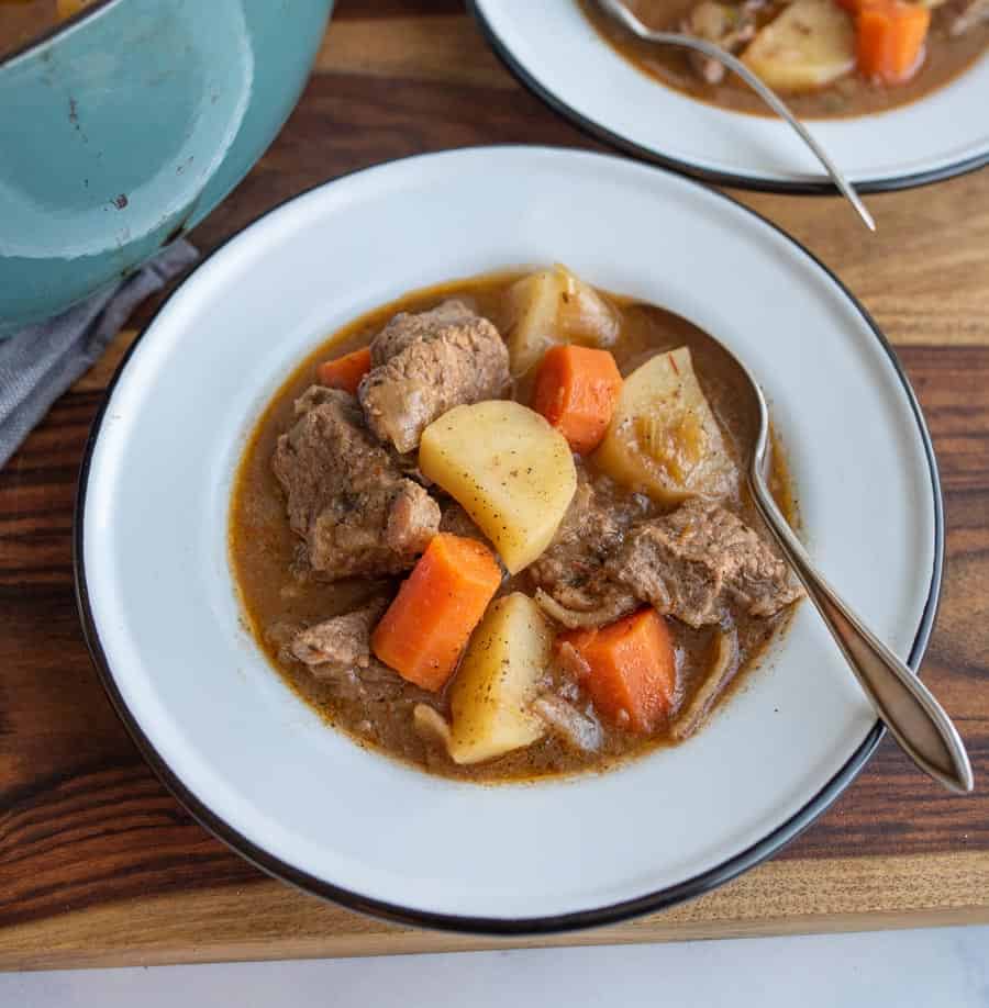 two bowls of hearty and traditional beef stew with a spoon.