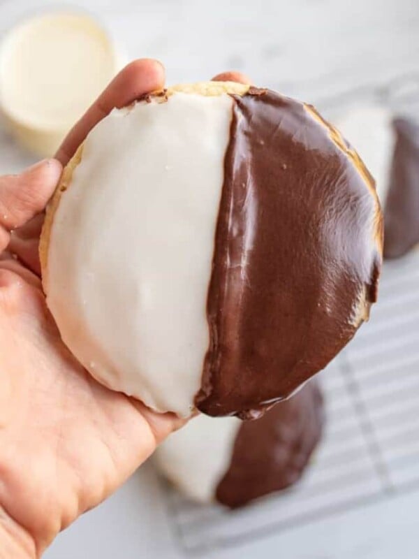 hand holding POV of one large black and white iced cookie exactly half and half split of each color