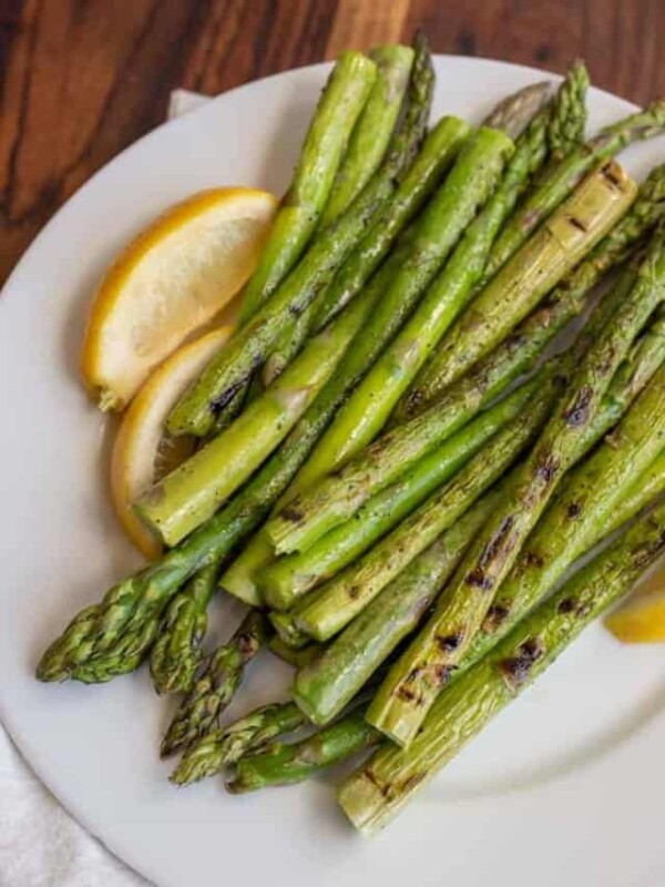 cooked asparagus and fresh lemon on a white plate