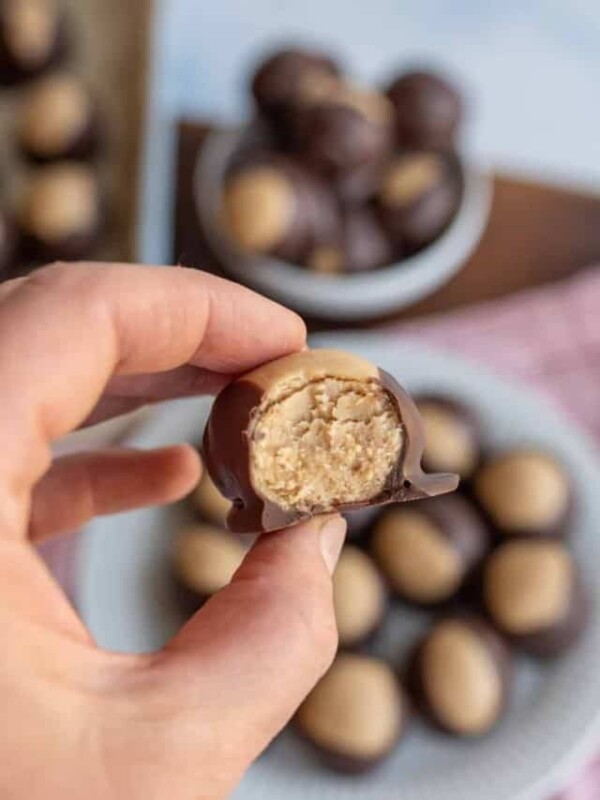 peanut butter chocolate buckeye bites POB of a hand holding and taking bite out of the chocolate exterior and filled center