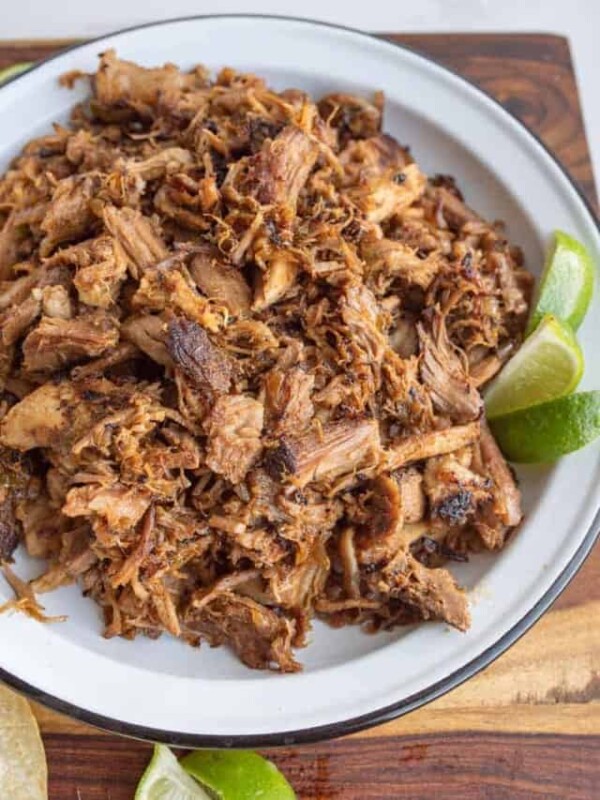 top view of shredded pork on a white plate with fresh lime