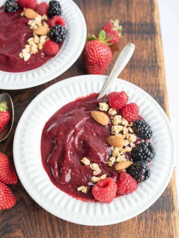 two white bowls with acia bowl recipe with fresh fruit, nuts, and granola