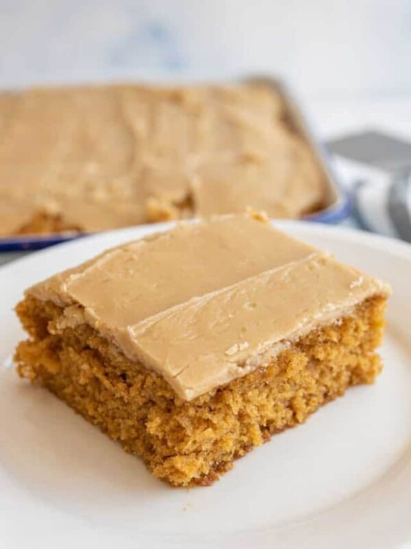 one square of pumpkin cake with caramel icing on a white plate