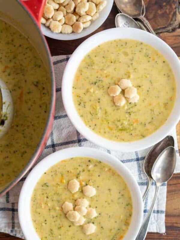 top view of two white bowls and red dutch pot with cheddar broccoli soup and oyster crackers