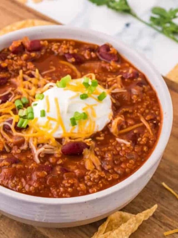 white bowl of vegetarian chili with soup cream and cheese on top