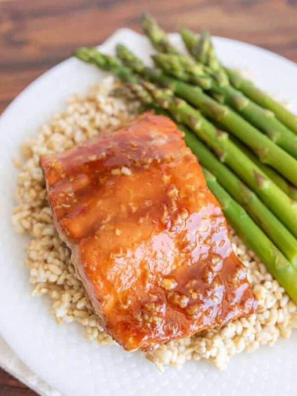 honey glazed salmon dinner on a plate over rice with asparagus as a side