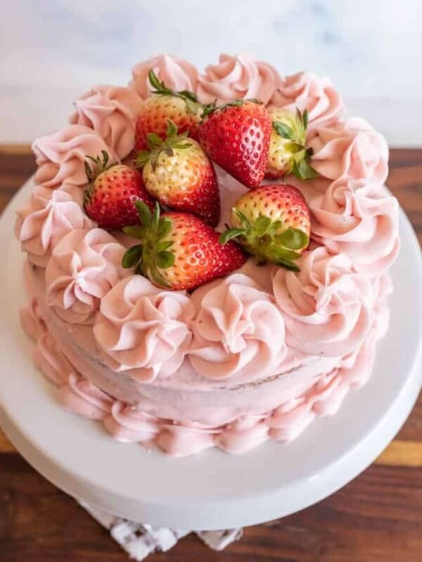 whole pink strawberry cake with strawberry buttercream and whole strawberries on top