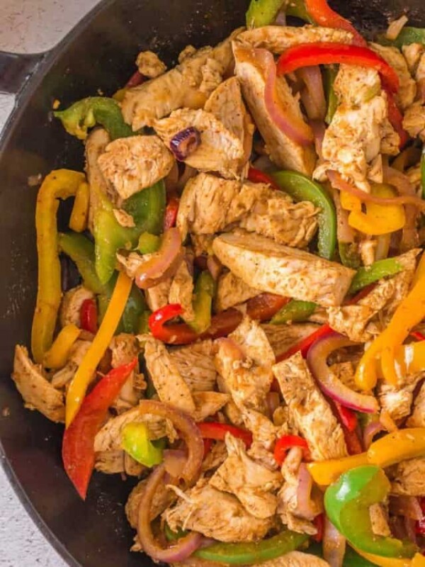 cast iron pan with chicken fajita meat and peppers cooked