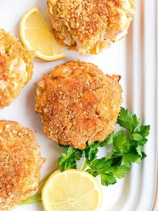 close up of a platter of cooked crab cakes and lemon slices