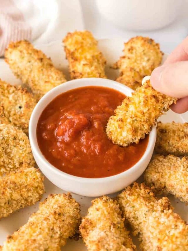 POV dipping air fryer mozzarella sticks in marinara sauce