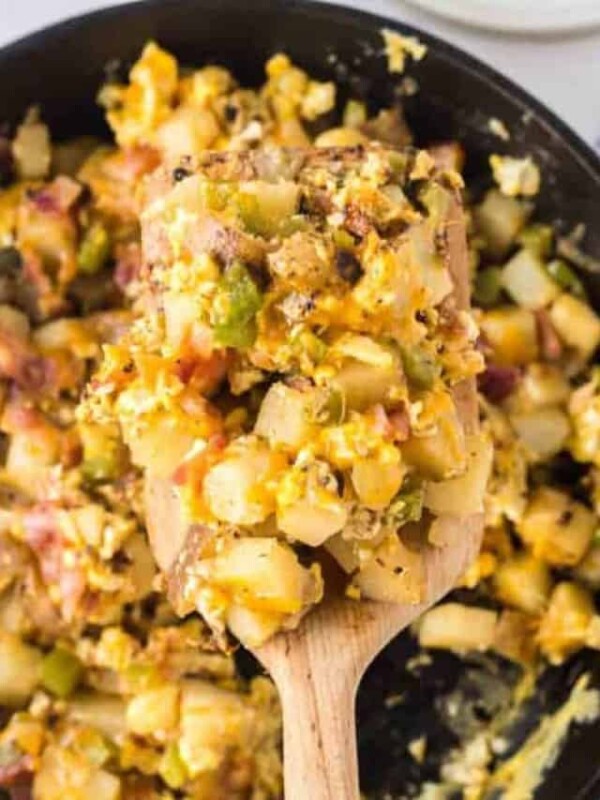 mixed up baked breakfast skillet with a serving scooped onto a wooden spatula up close