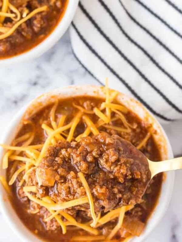 top view POV with a spoon full of Cincinnati chili served into small white dishes with shredded cheese on top