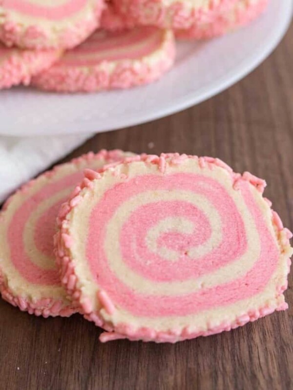 close up of pink and tan swirl decorated pinwheel cookies with pink sprinkles