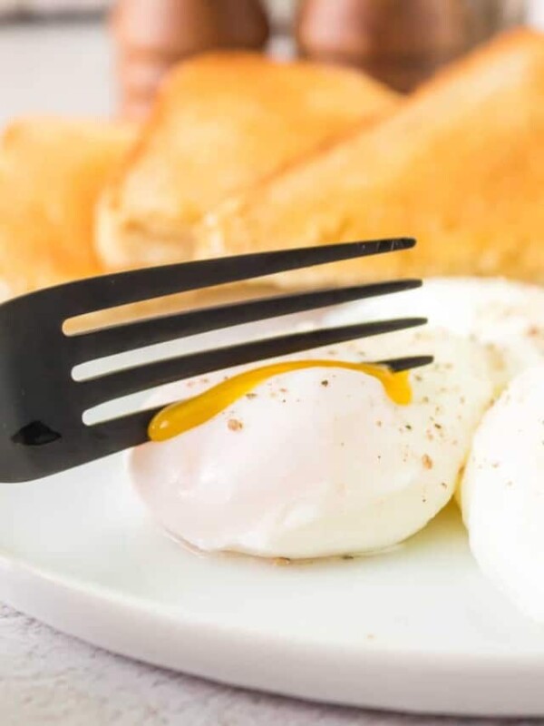 fork cutting a poached egg and its gooing out