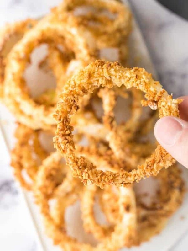 POV hand holding a circle crispy breaded and baked onion ring