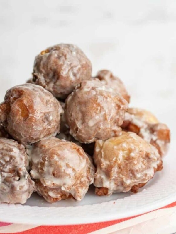 small round apple fritter bites stacked onto a plate