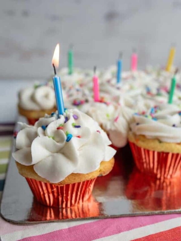 vanilla cupcakes with white icing and rainbow sprinkles for birthday cupcakes with a candle in each