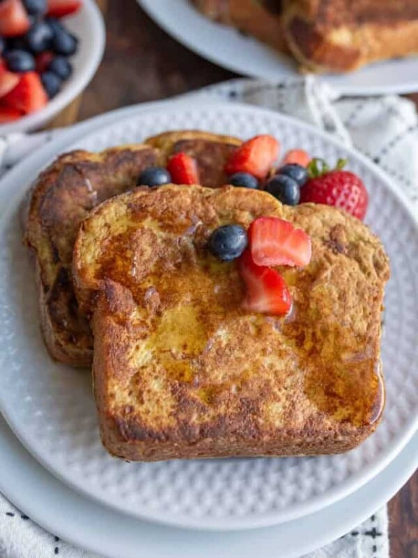 syrup over thick sliced brioche french toast with berries on top