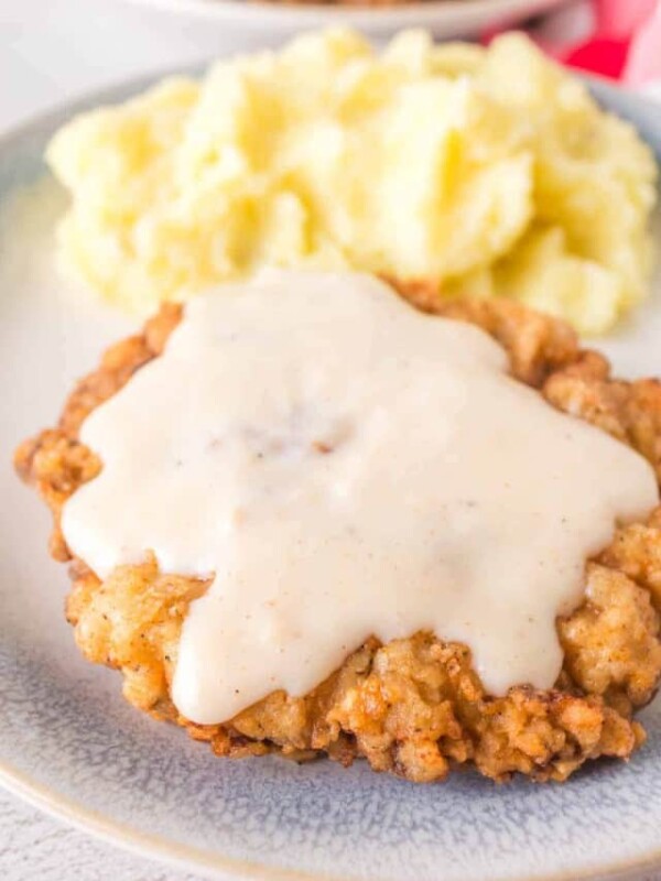 crispy chicken fried steak on a plate with gravy on top and mashed potatoes