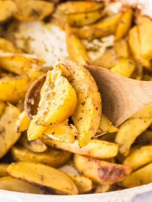 close up of a spoonful of greek potatoes cut in wedges and seasoned