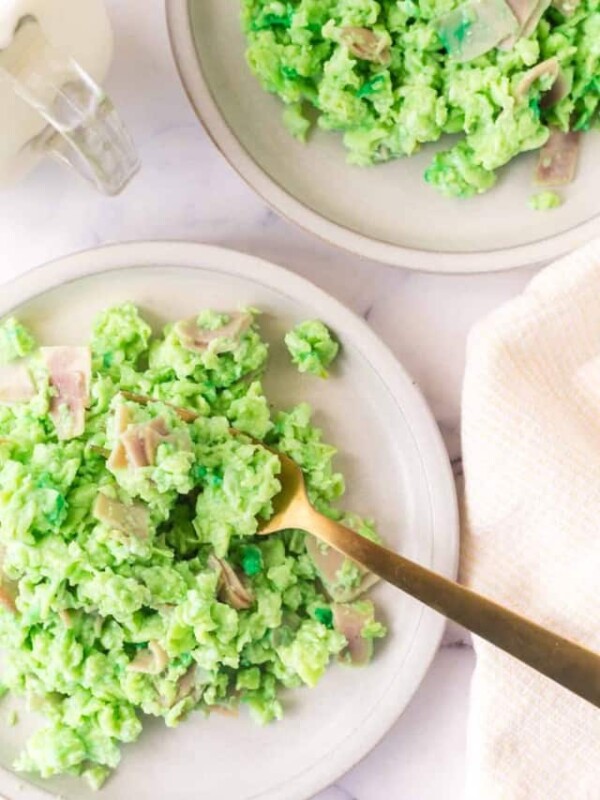 green colored scrambled eggs with pieces of ham on a white plate