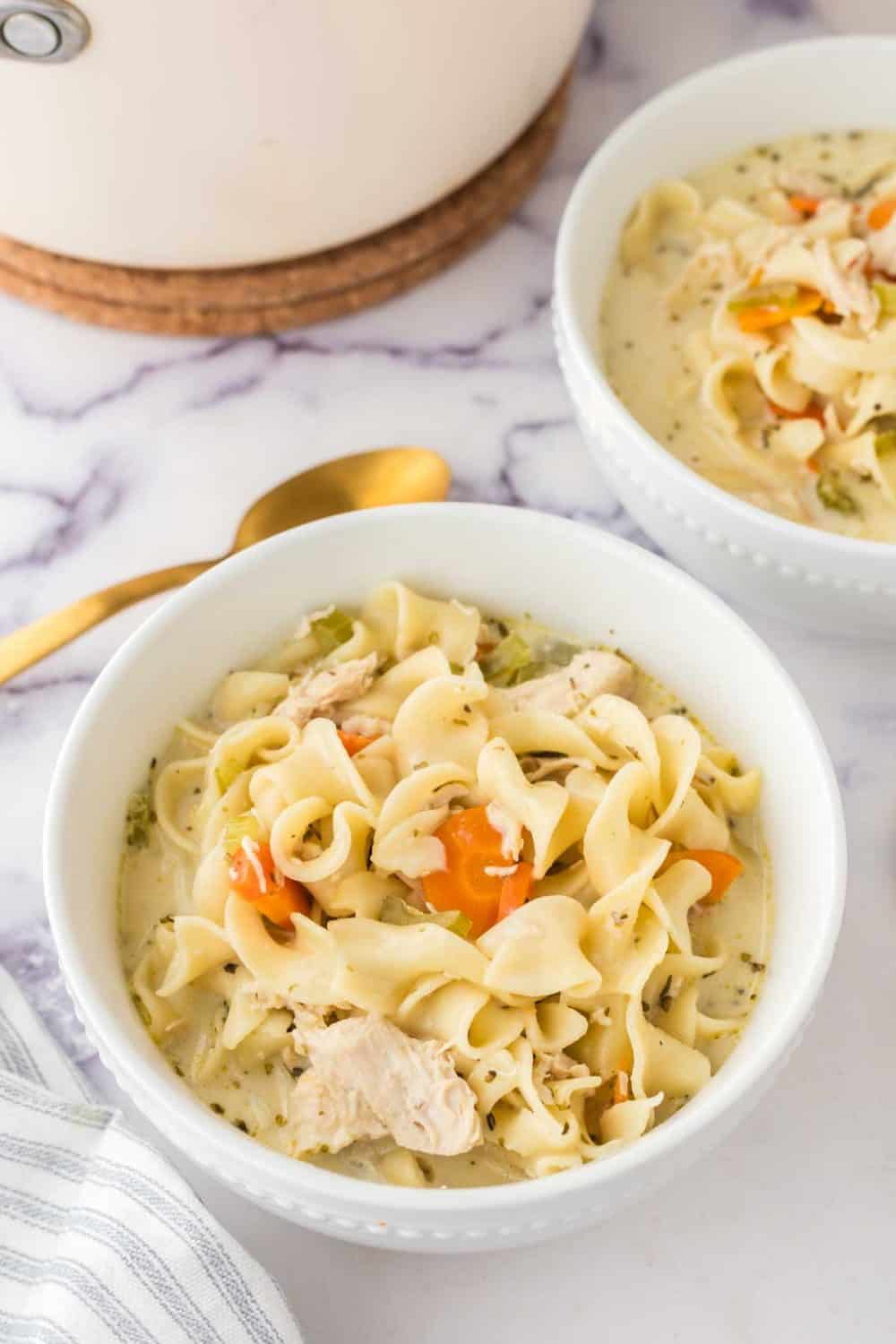 top view of a white bowl of creamy chicken noodle soup