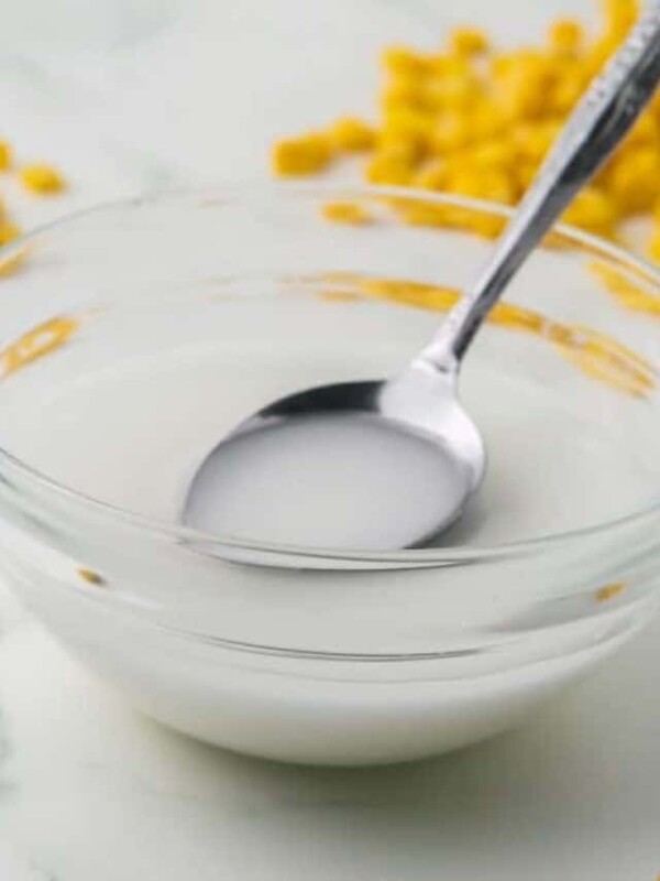 corn starch slurry bowl with a bottle of corn starch and corn kernels all around