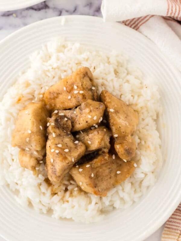 top view close up of honey chicken cubes over rice on a white plate